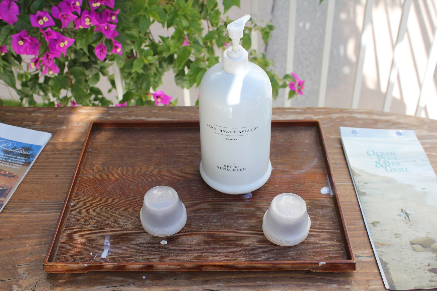 a white bottle and two cups on a wooden tray