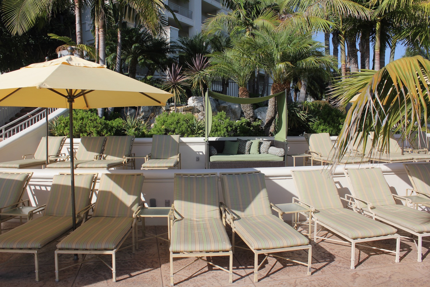 a group of lounge chairs and umbrellas on a patio