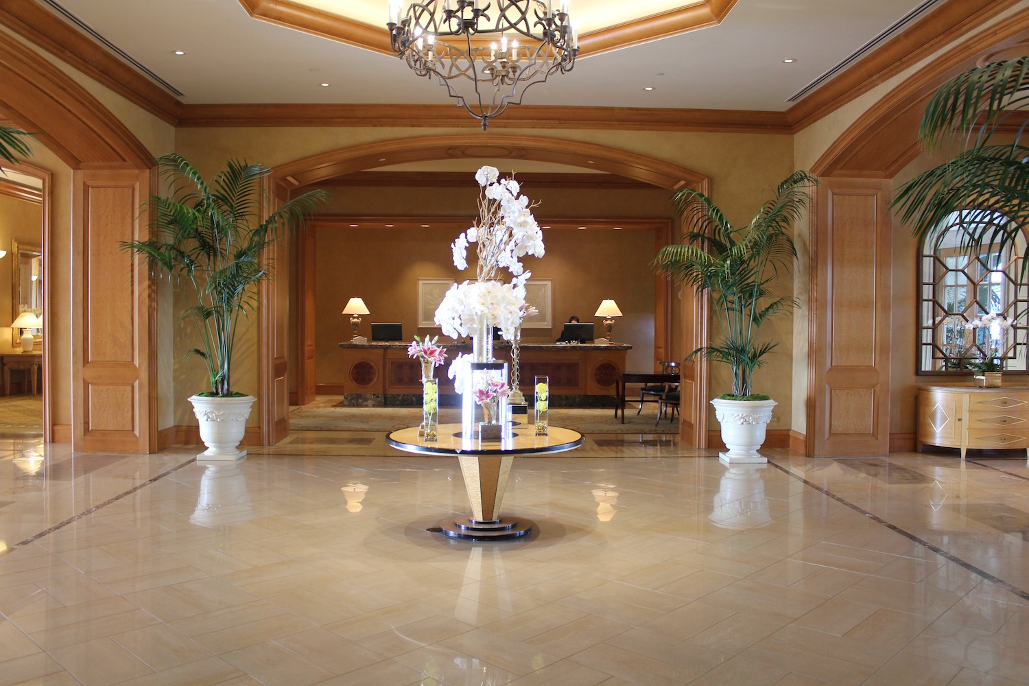 a lobby with a table with flowers and palm trees