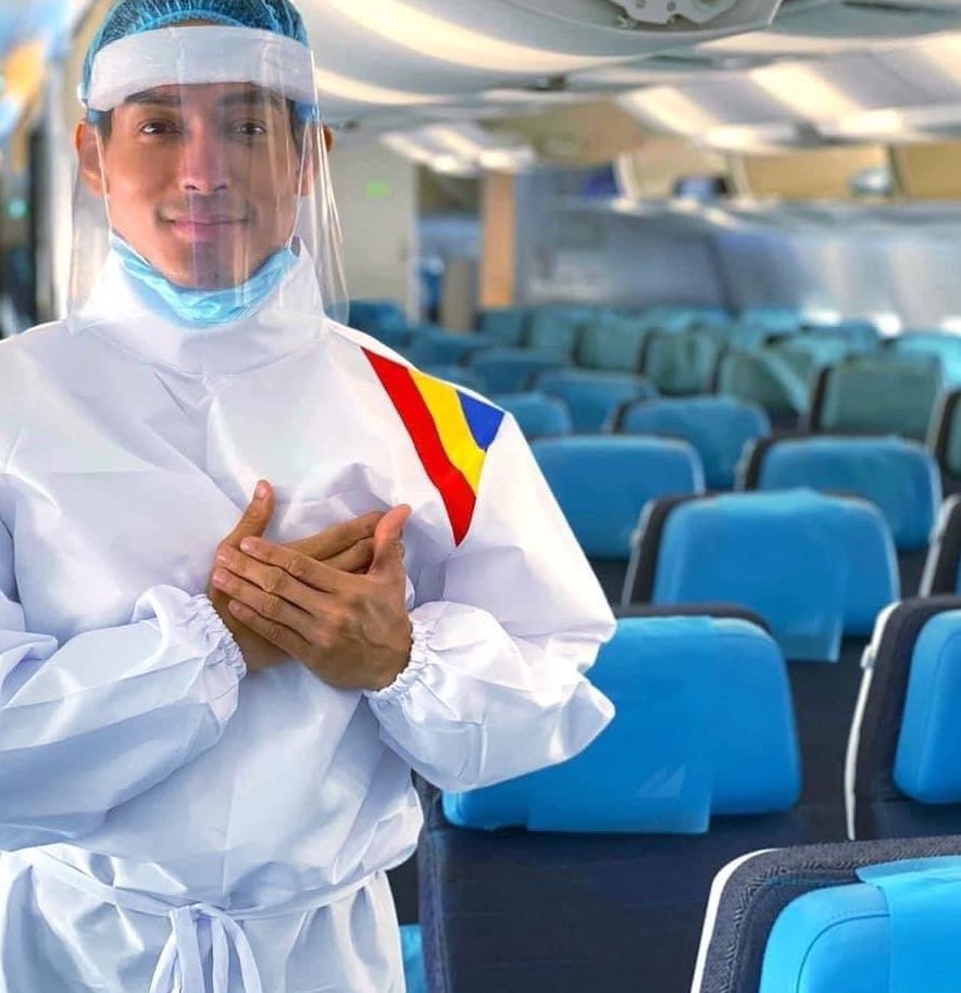 a man in a white suit and face shield with his hands on his chest