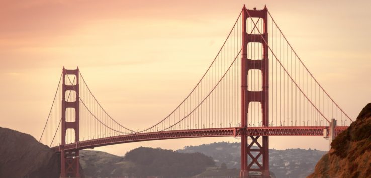 Golden Gate Bridge over water with a pink sky