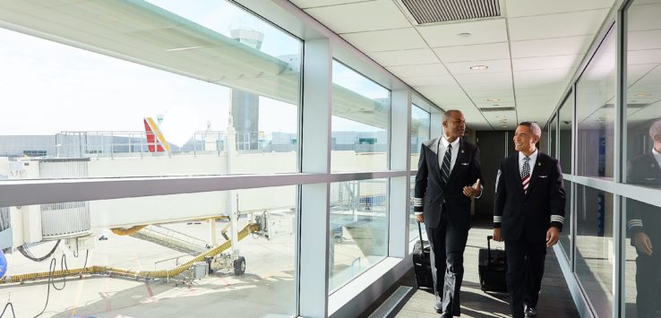 a group of men walking down a hallway with luggage