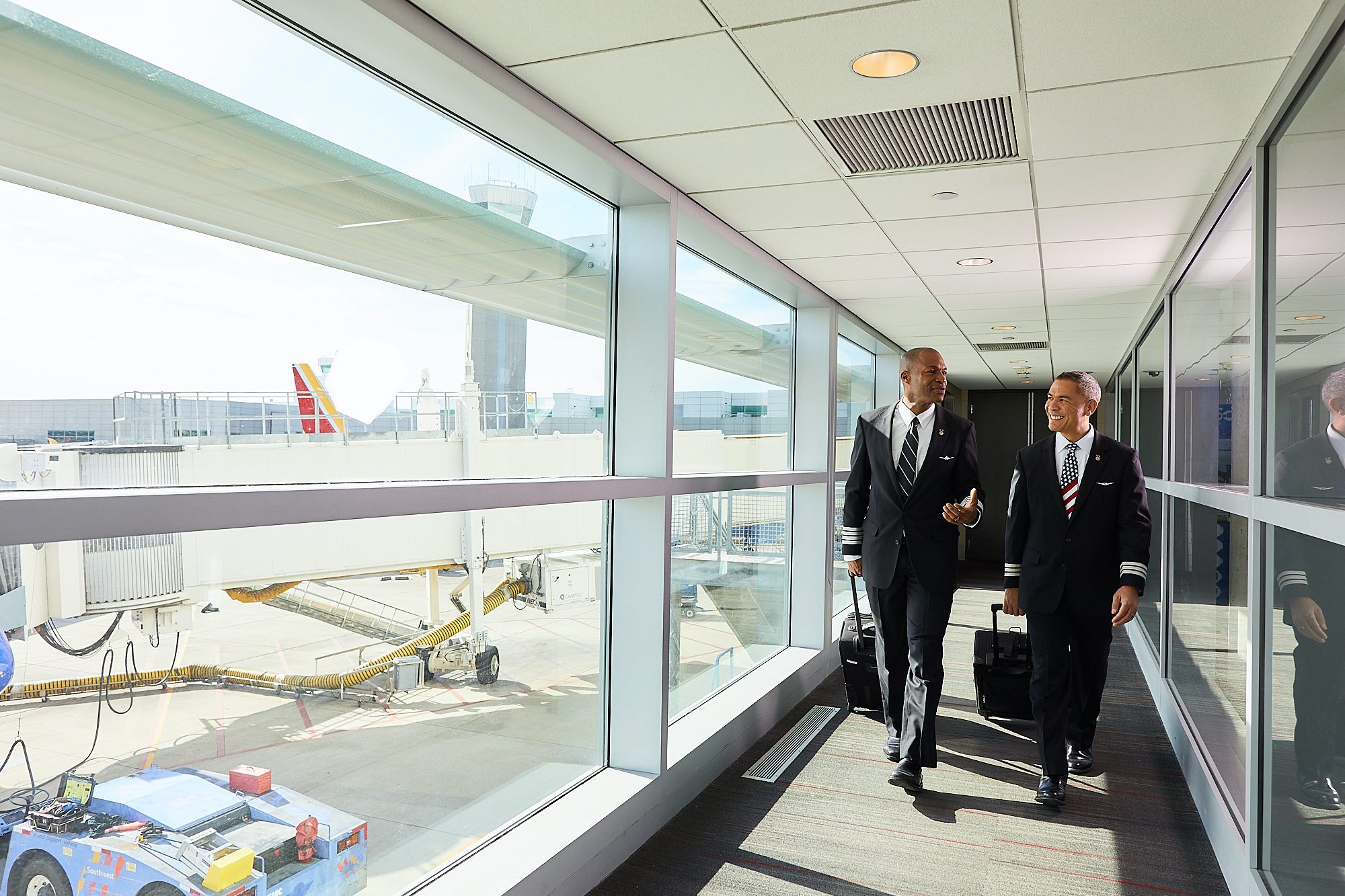 a group of men walking down a hallway with luggage