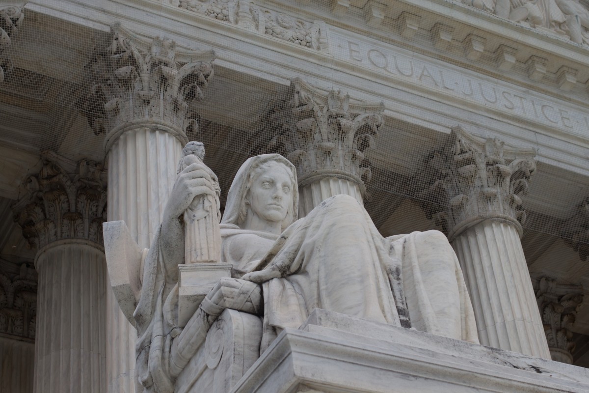 a statue of a woman sitting on a pillar