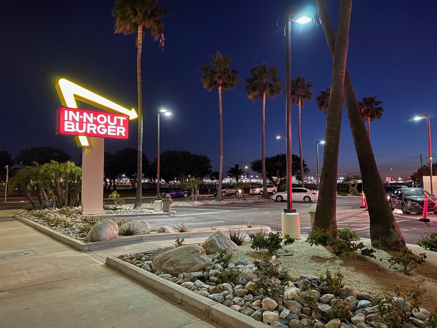 a sign with palm trees and a parking lot