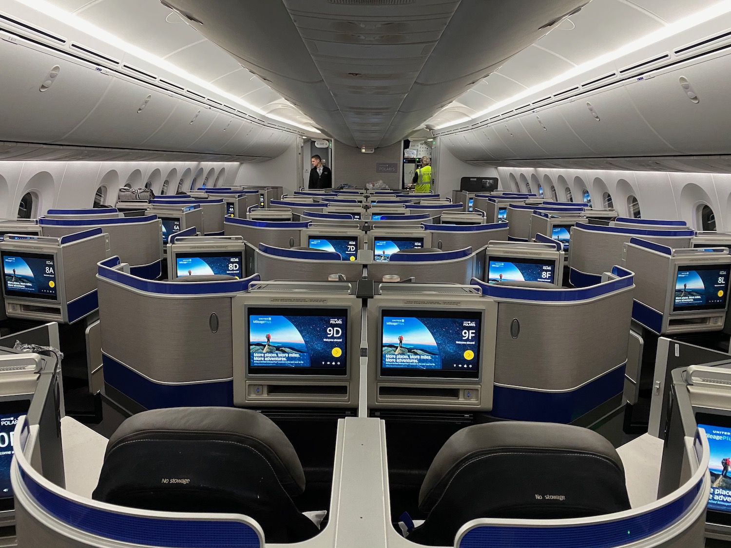 a row of seats with monitors in the middle of an airplane