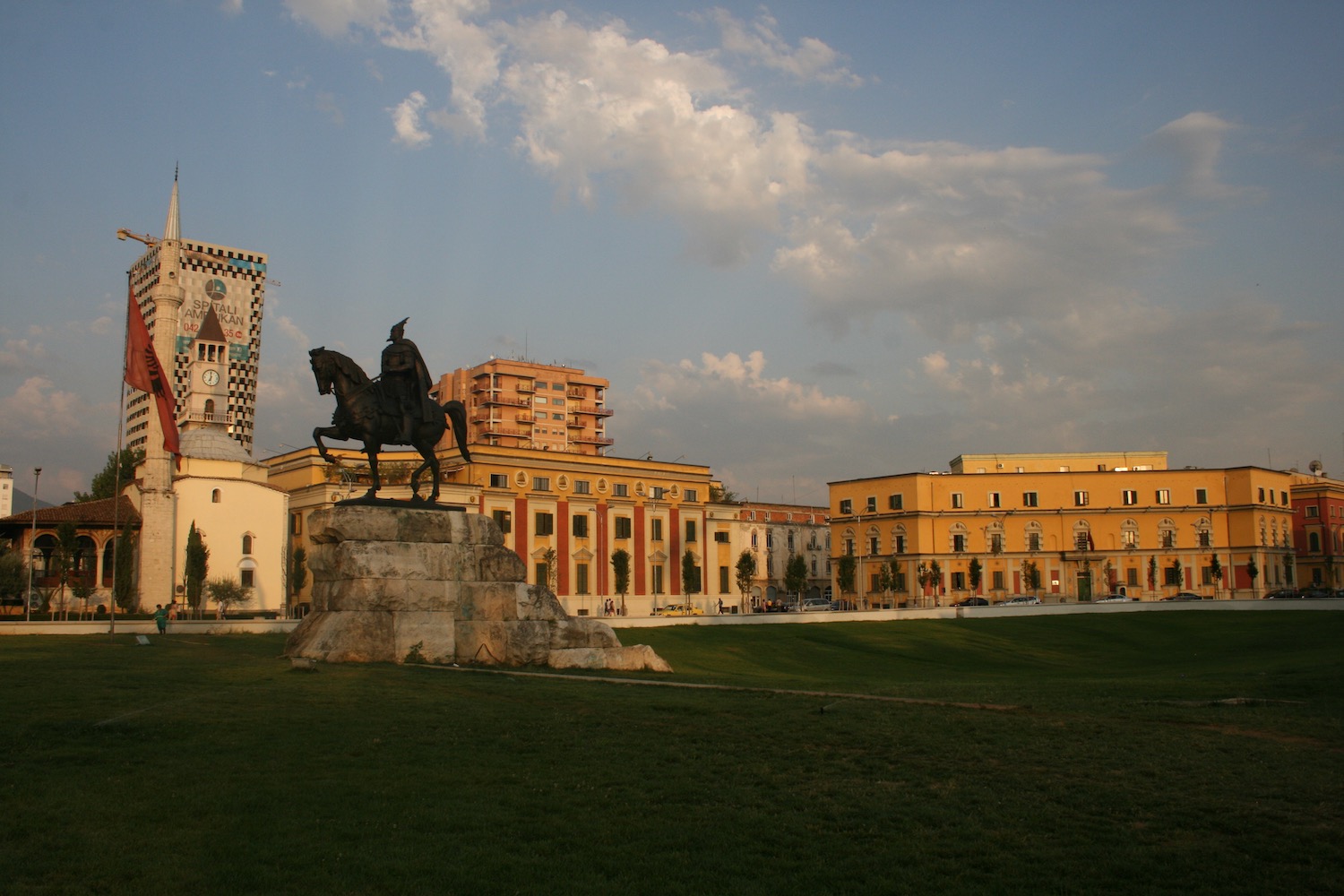 a statue of a man on a horse in a park with buildings in the background