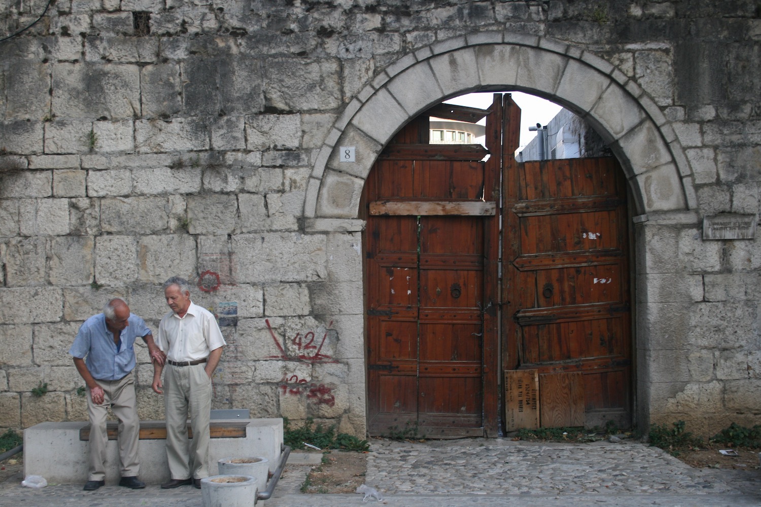 a couple of men standing in front of a stone wall