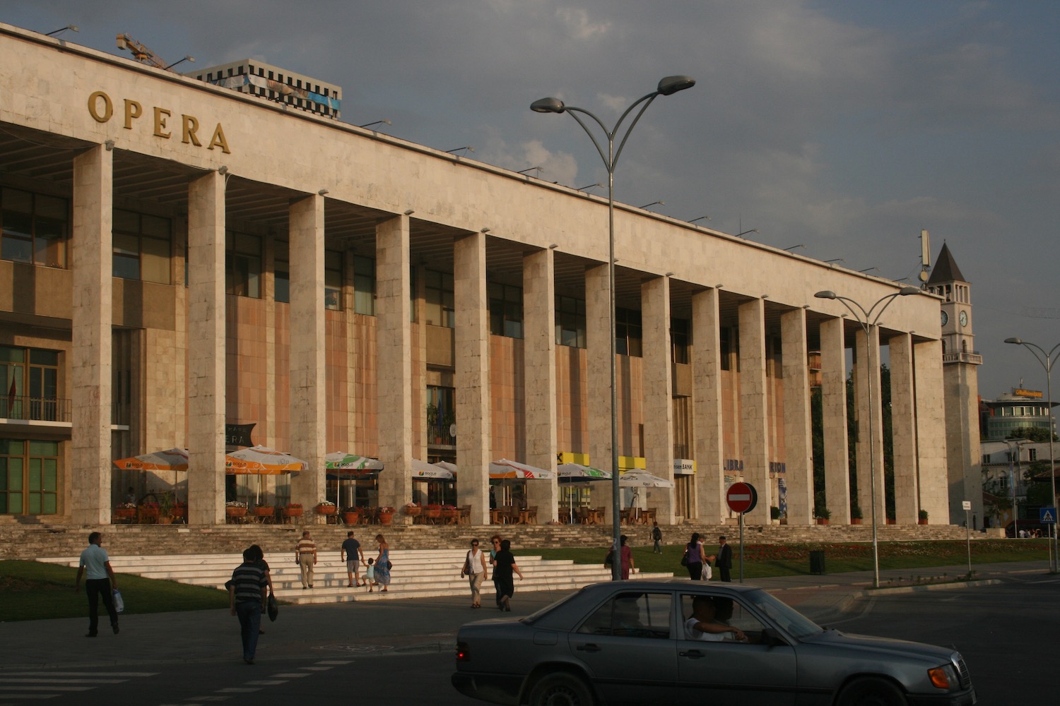 a building with columns and people walking on the street