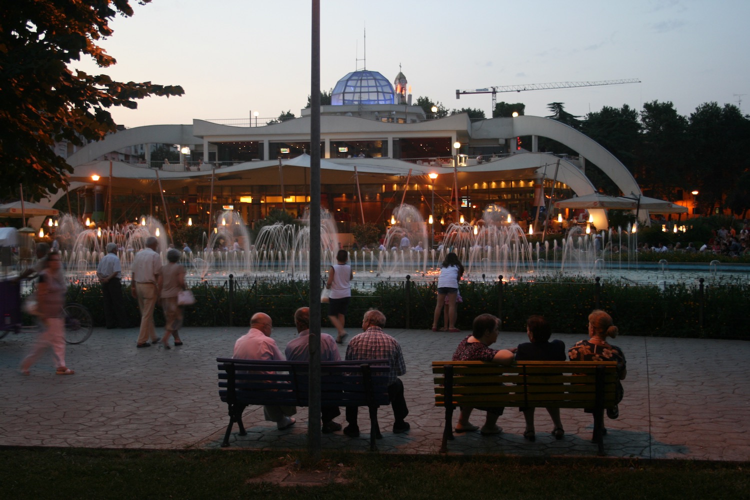 a group of people sitting on benches in front of a fountain