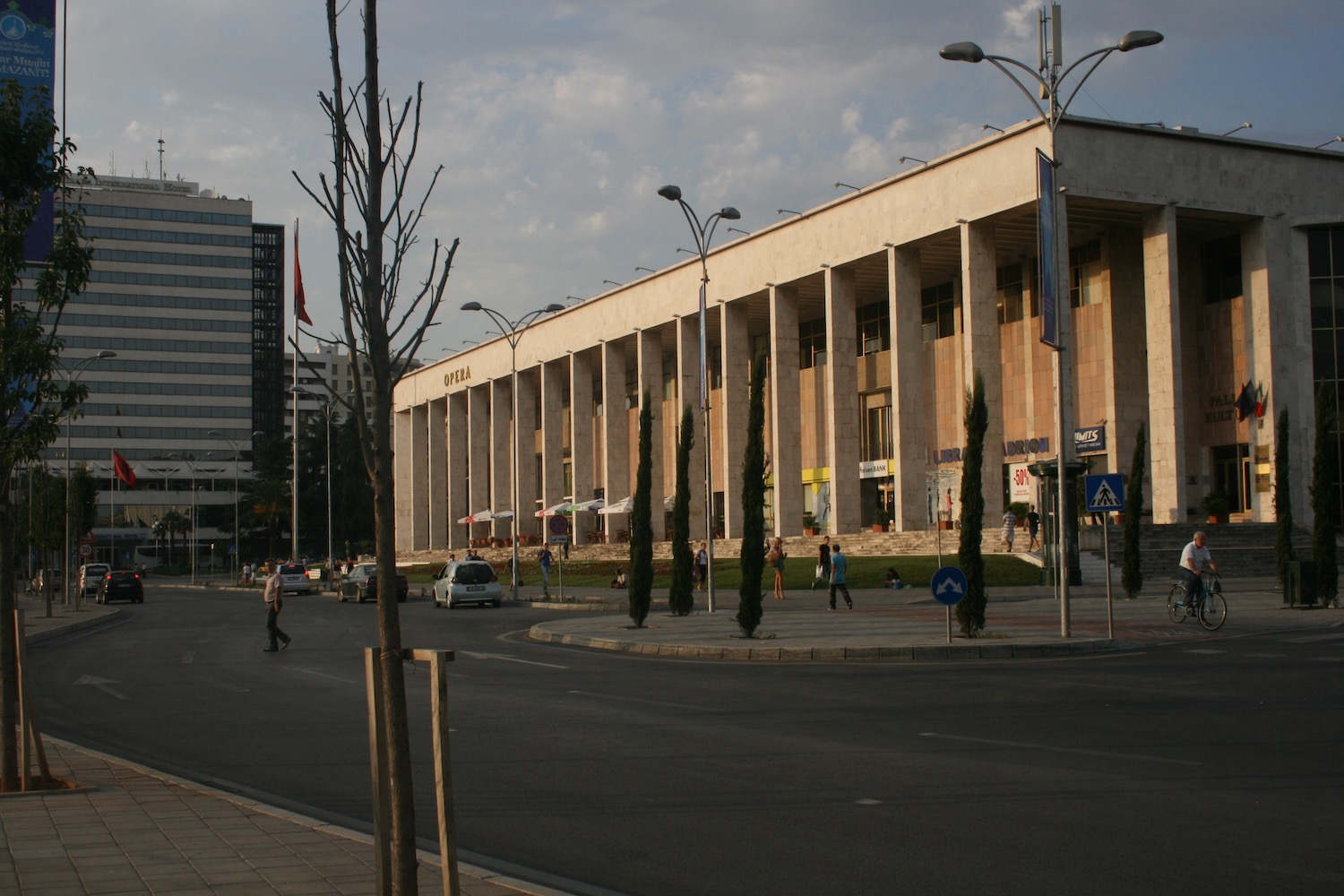 a building with columns and people walking on the street