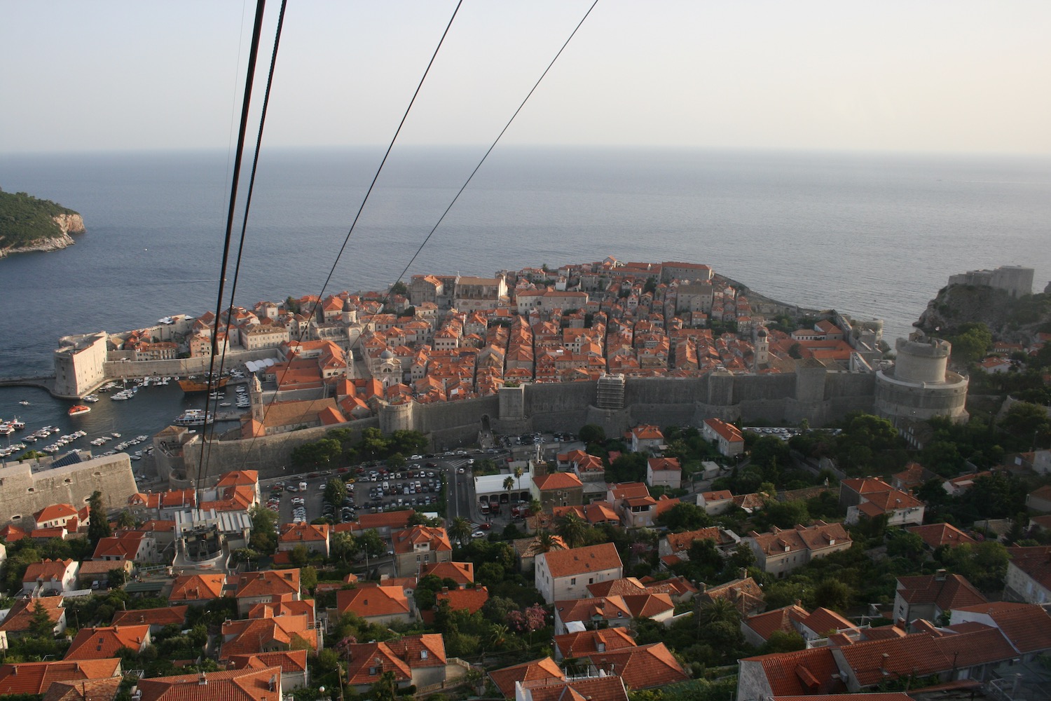 a city with red roofs and a stone wall and a large body of water