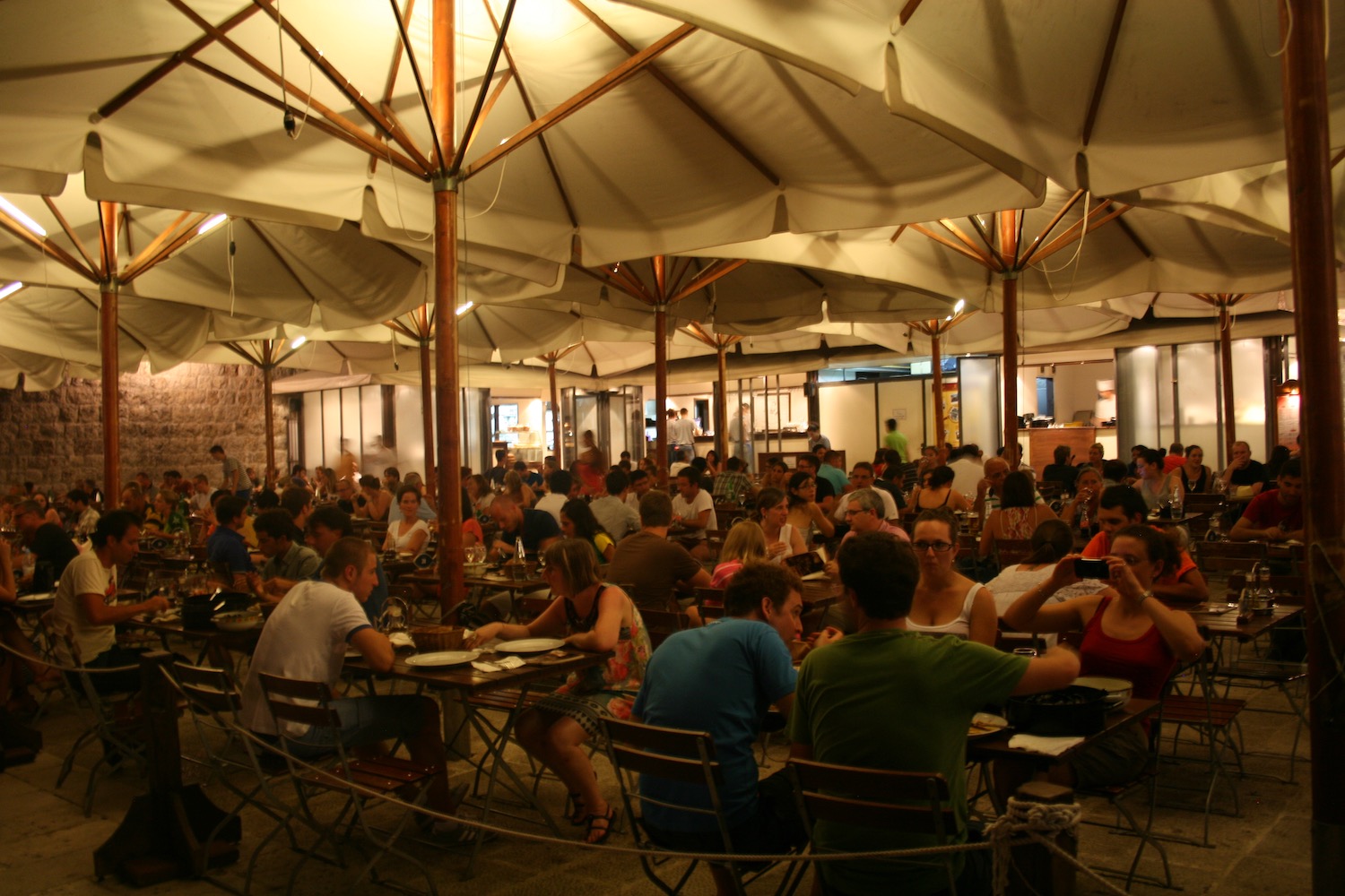 a group of people sitting at tables under a large umbrella