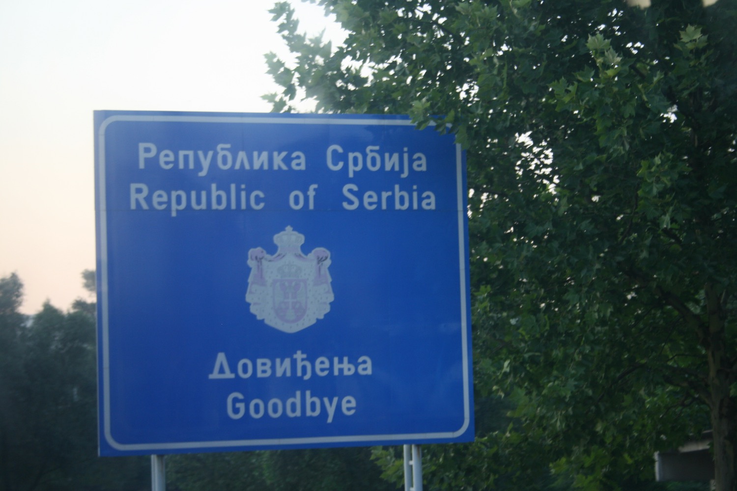 a blue sign with white text and a coat of arms on it