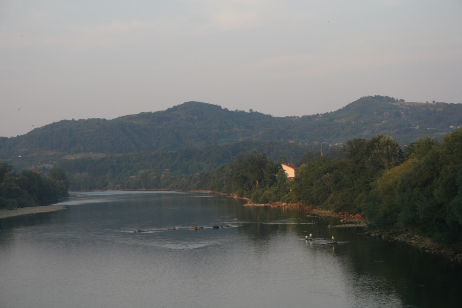 a body of water with trees and a house in the distance