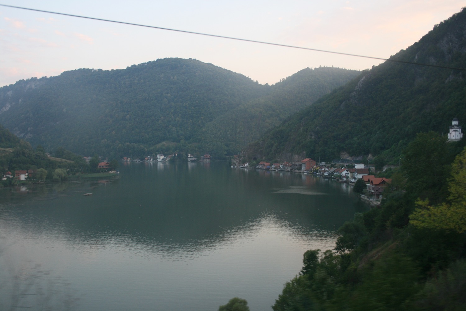 a body of water with houses and mountains in the background