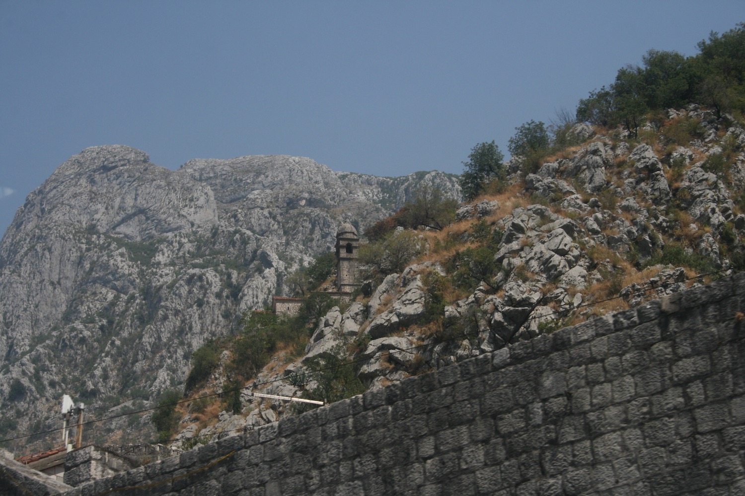 a stone wall with a tower on top of a mountain