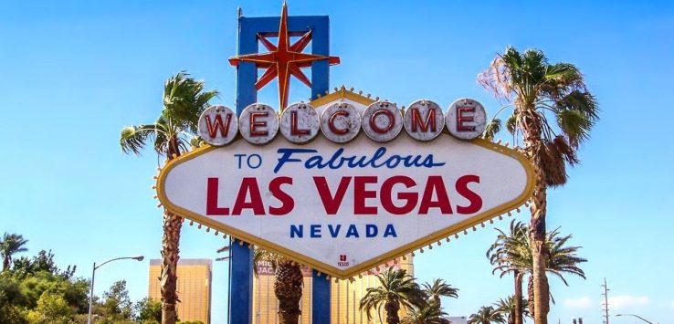 a sign with palm trees and a star on it with Welcome to Fabulous Las Vegas sign in the background