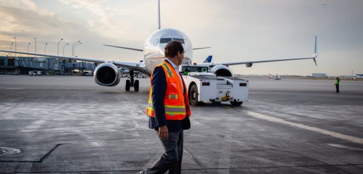 a man walking on a runway with a plane in the background