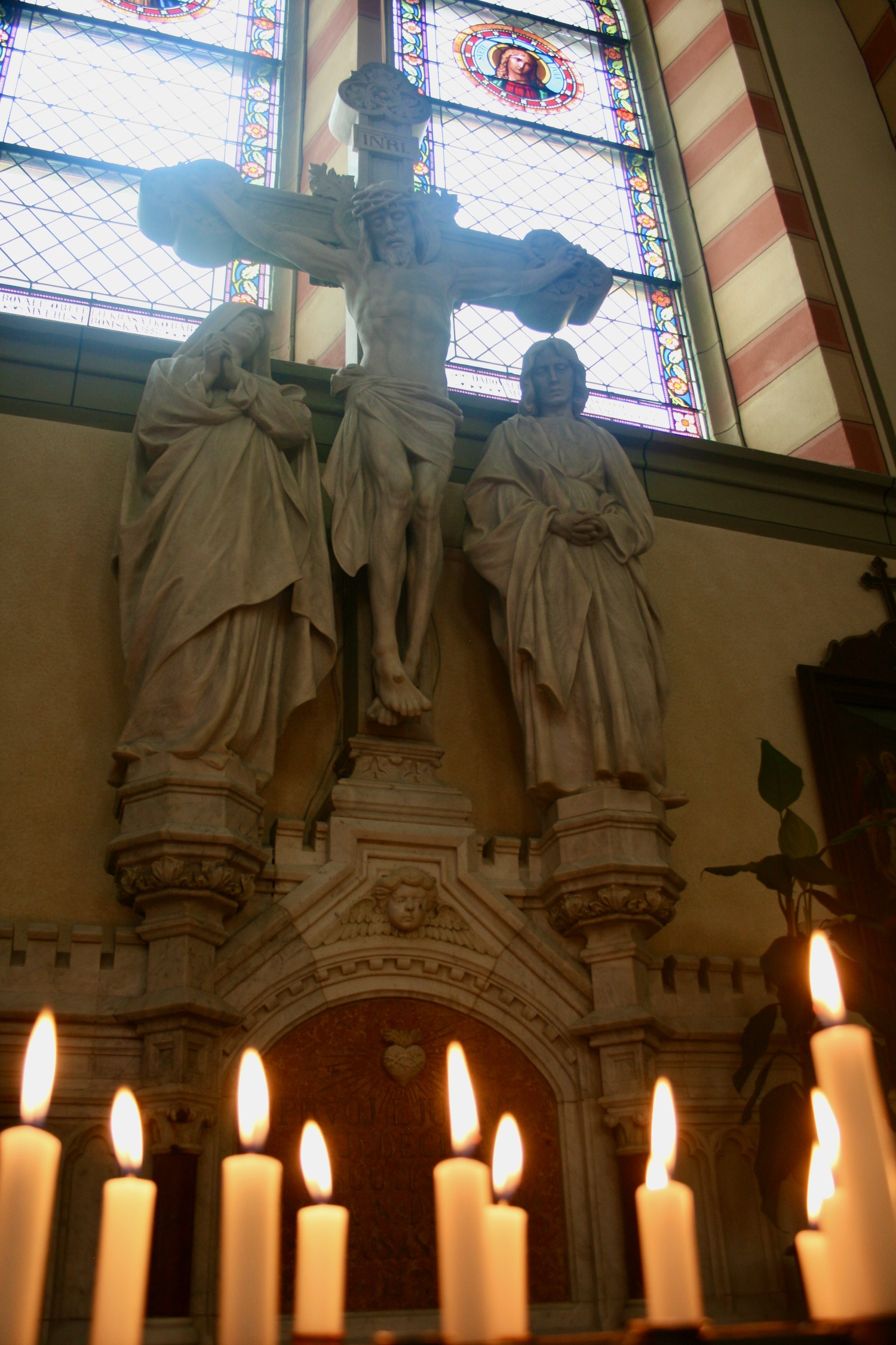 a statue of a man on a cross with a woman and a stained glass window