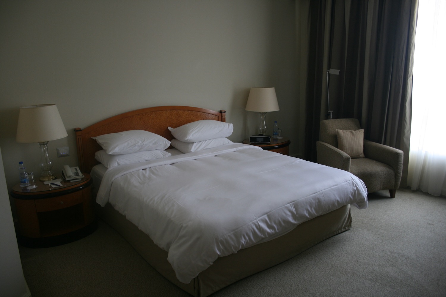 a bed with white sheets and pillows in a hotel room