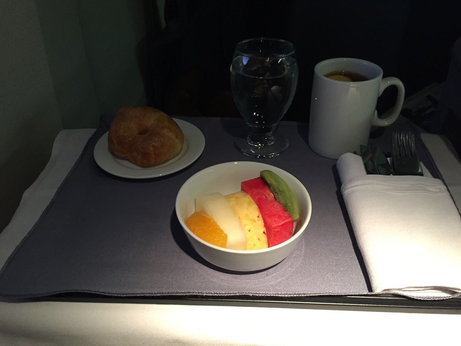 a bowl of fruit and a croissant on a table