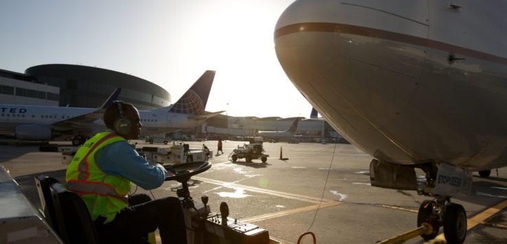 a man in a yellow vest and headphones sitting in front of a plane