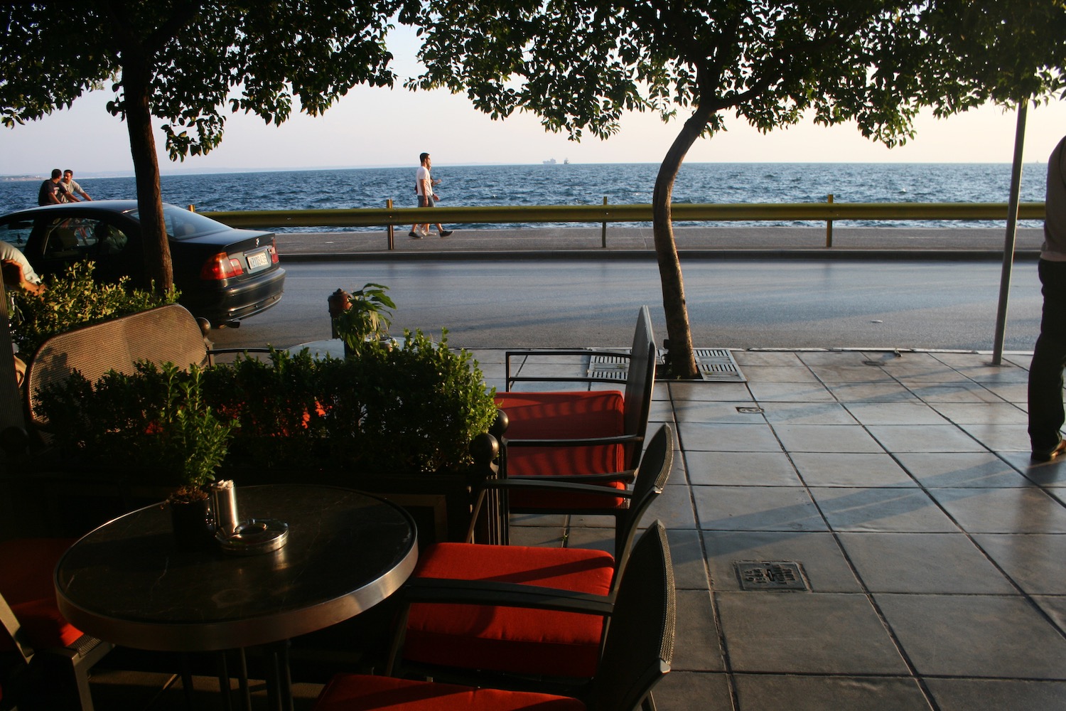 a table and chairs on a sidewalk by the water