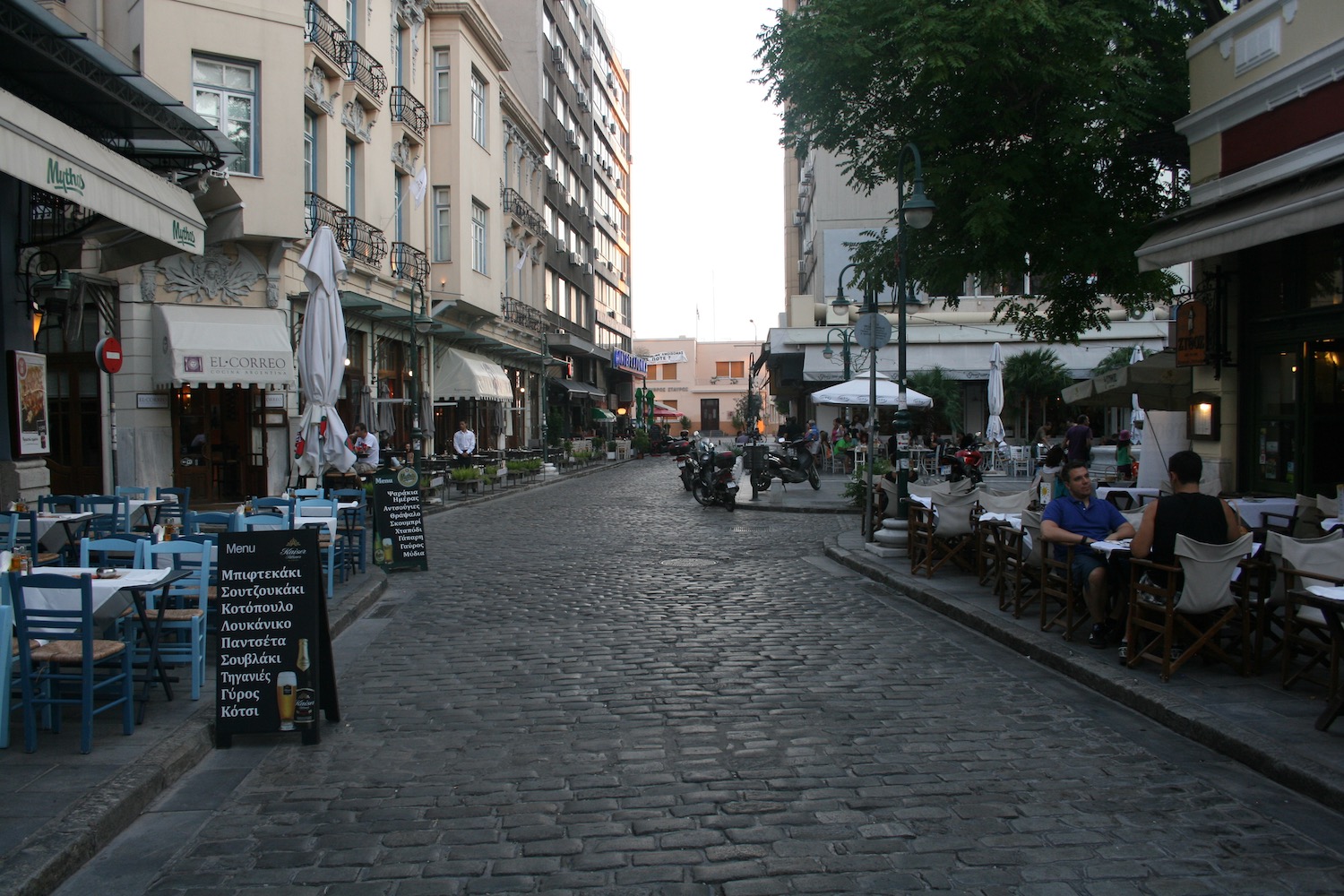 a street with people sitting at tables and chairs