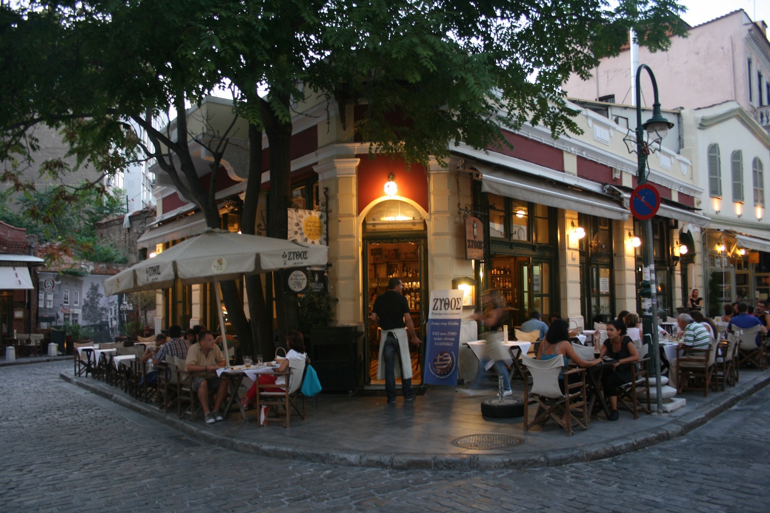a group of people sitting at tables outside a restaurant