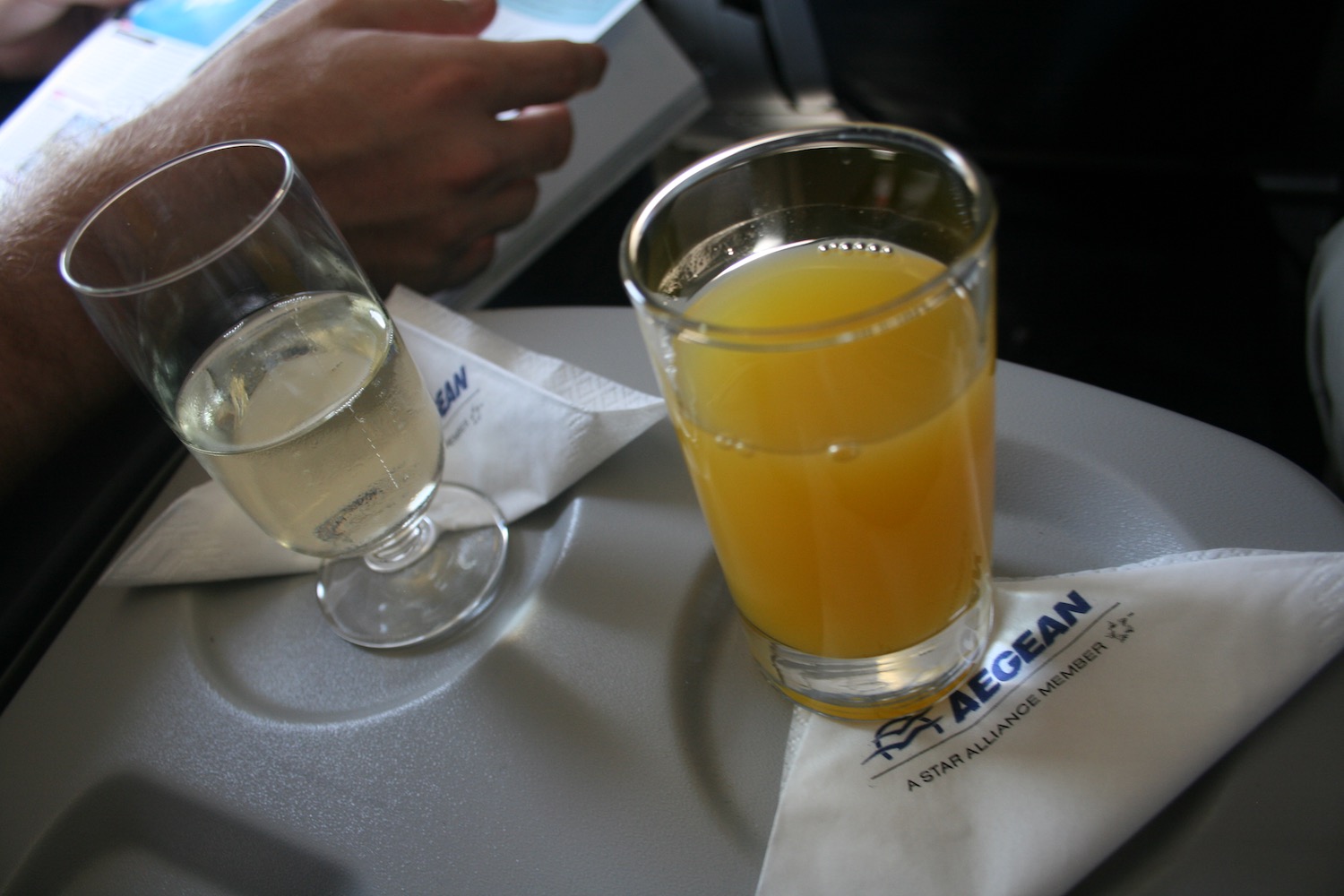 a glass of orange juice and a napkin on a tray