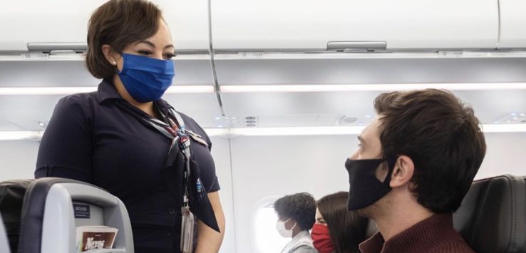 a woman wearing a face mask and standing in a plane