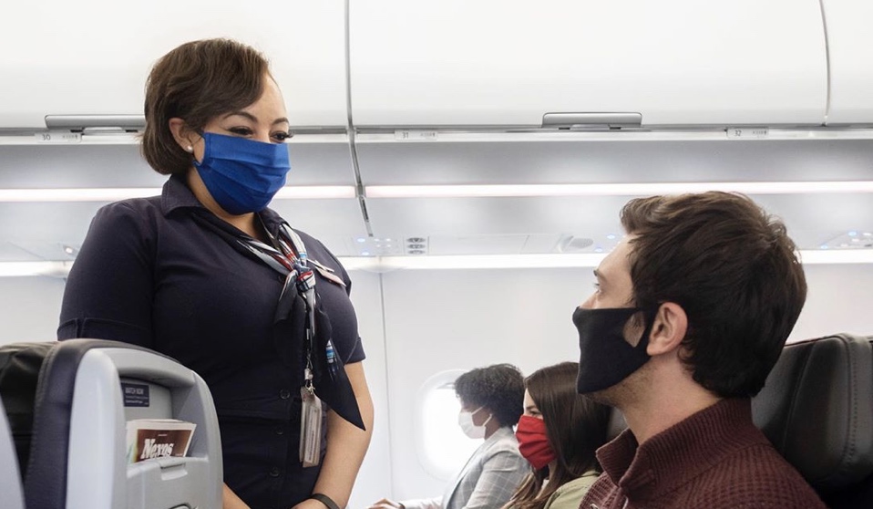 a woman wearing a face mask and standing in a plane