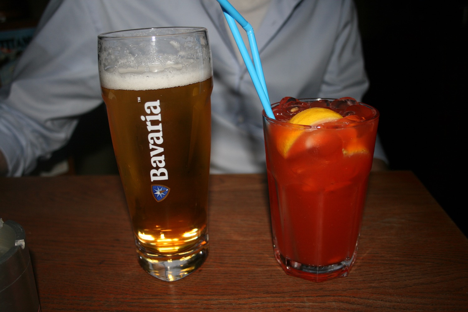 a glass of beer and a glass of liquid with straws