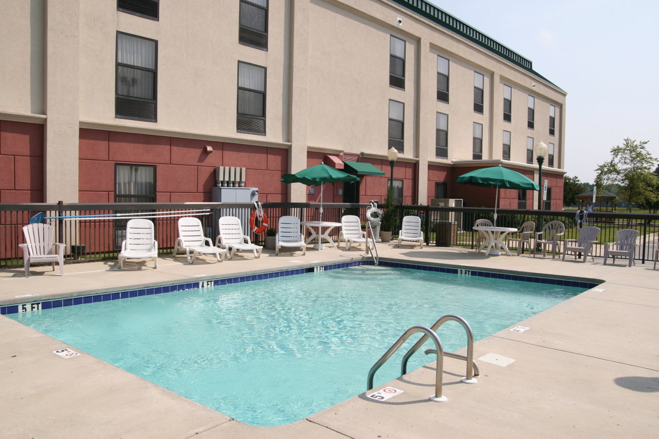 a pool with chairs and umbrellas in front of a building