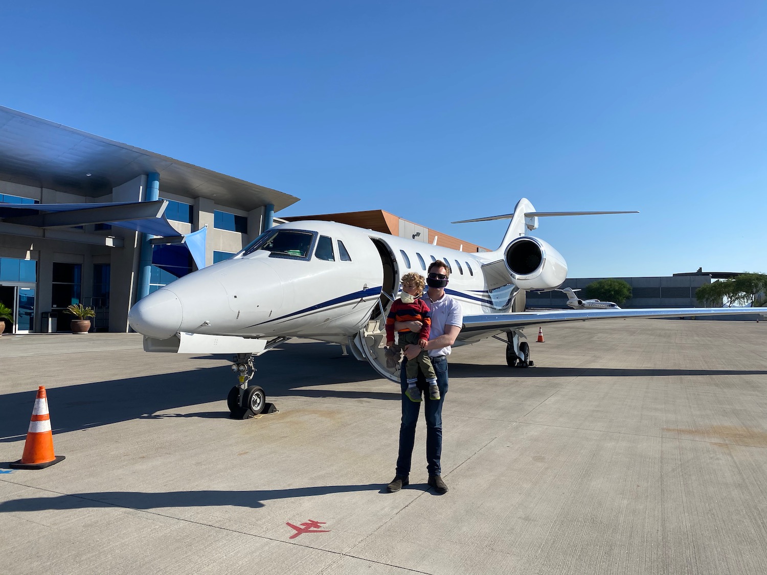 a man holding a child in front of a plane