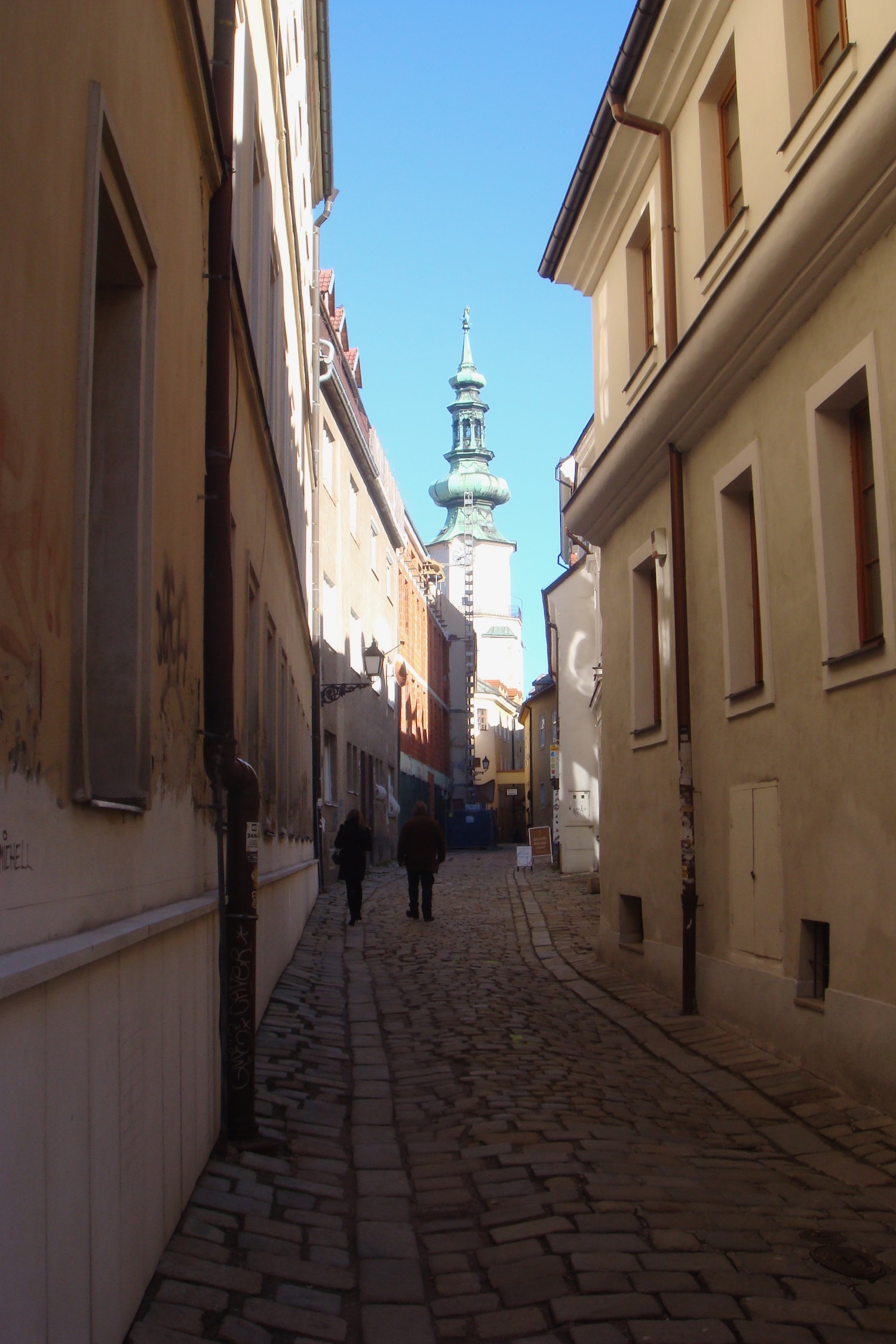 a couple of people walking down a narrow street
