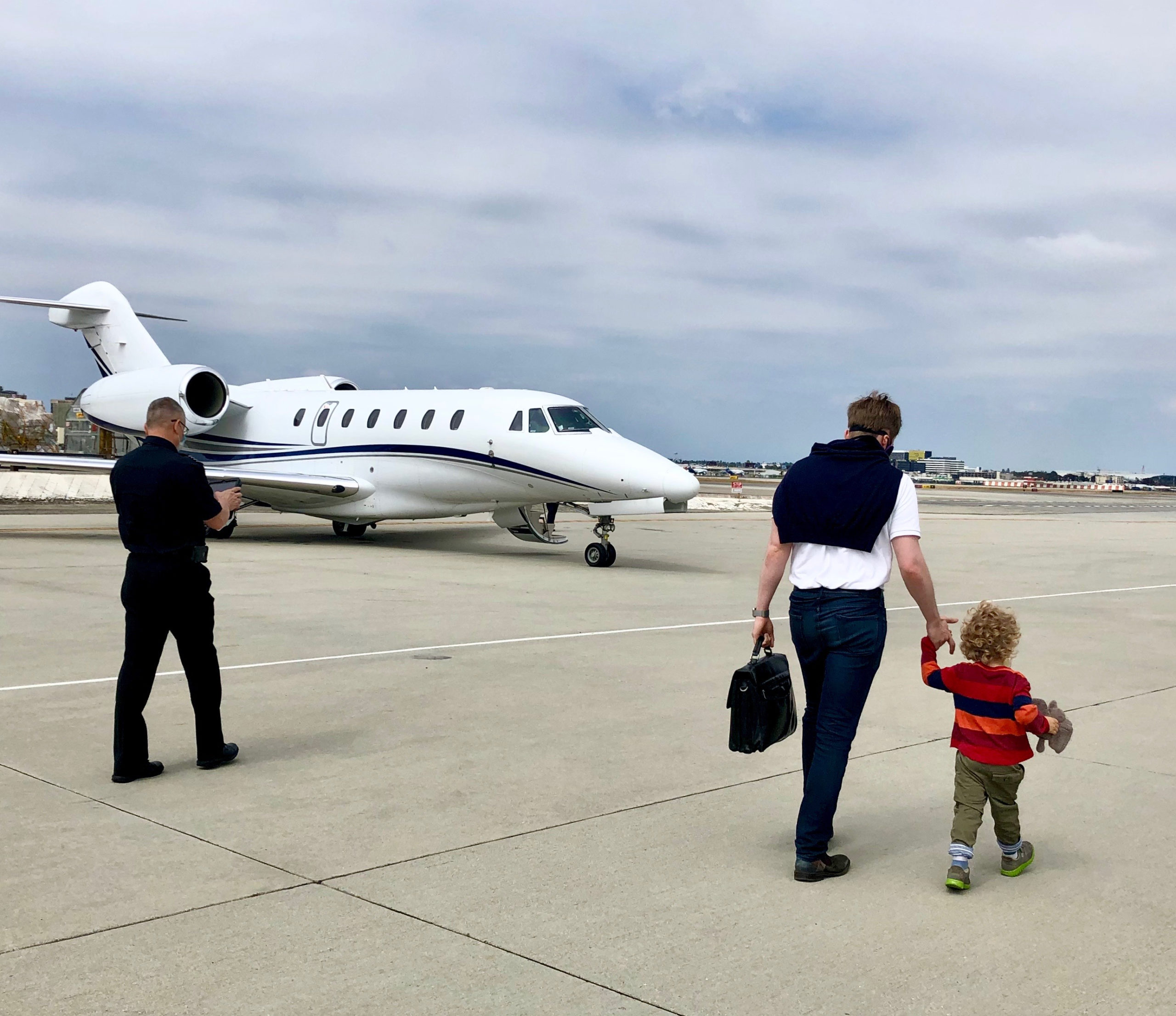 a man and child walking on a runway with a plane