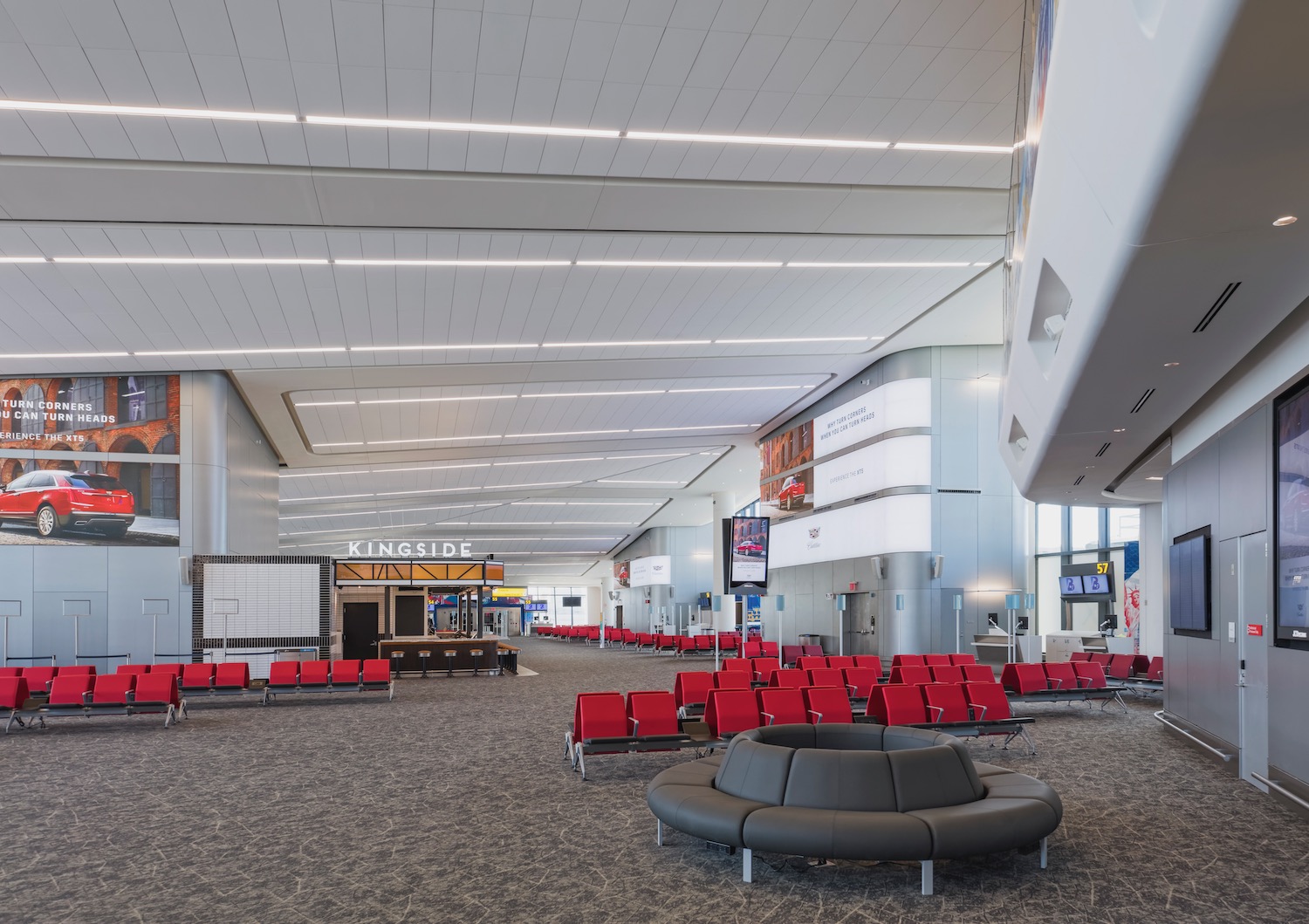 an airport terminal with red chairs and a large round table