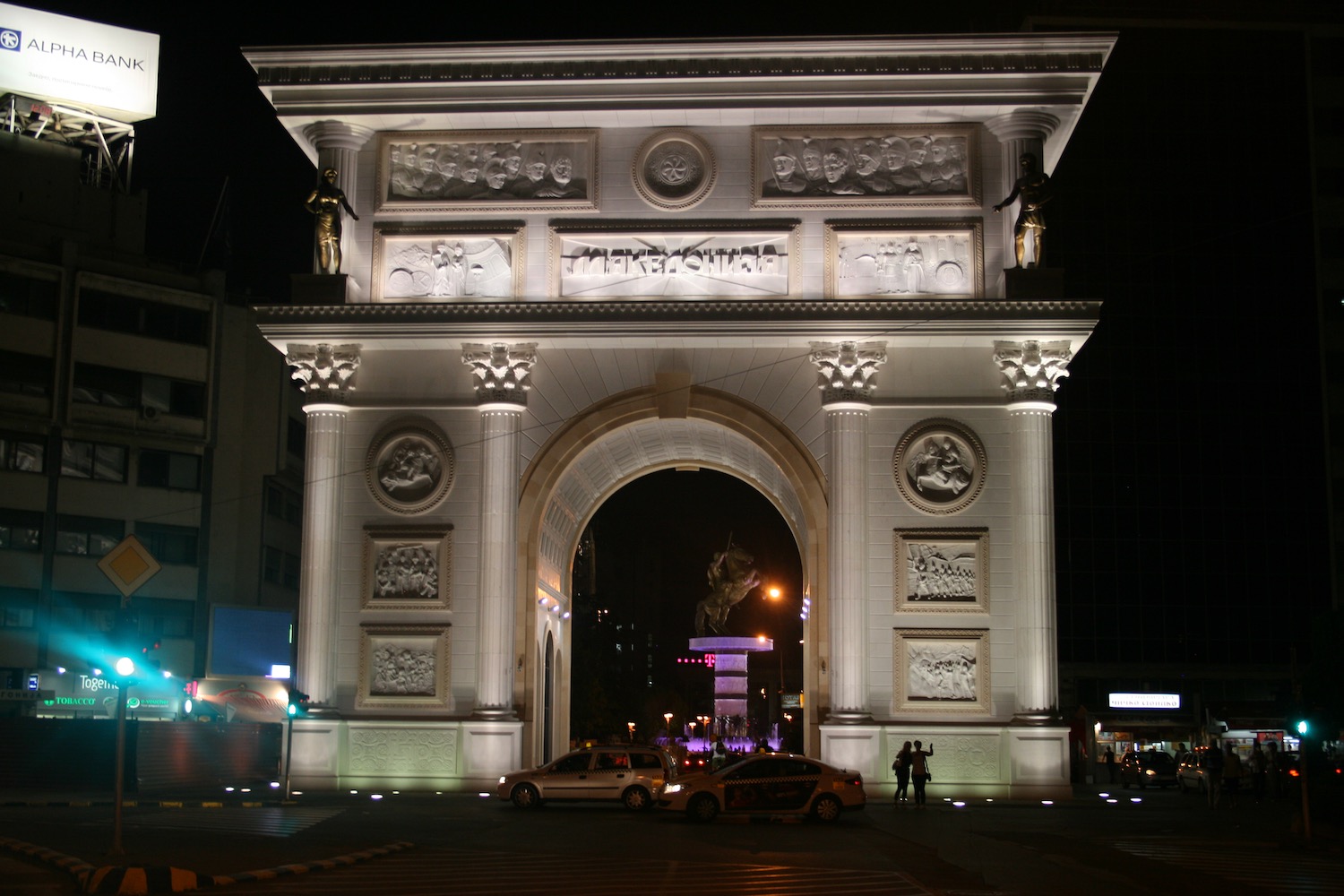 a large white archway with statues and a statue in the middle