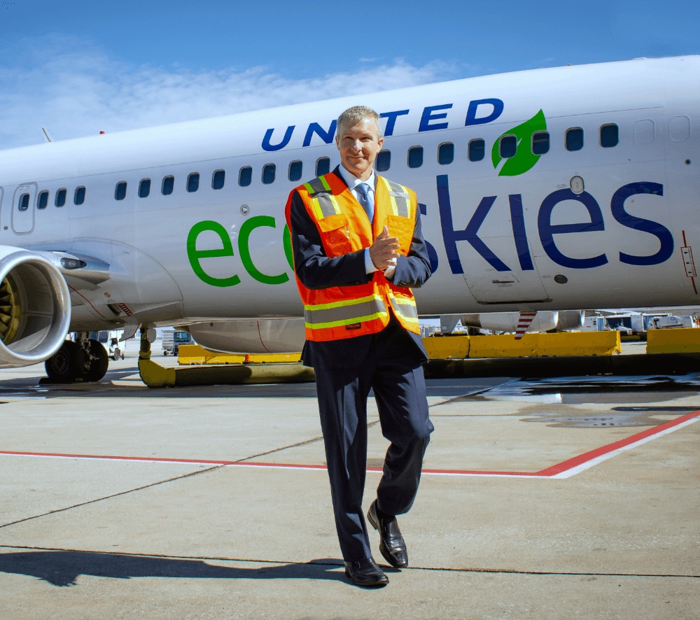 a man in a safety vest walking in front of an airplane