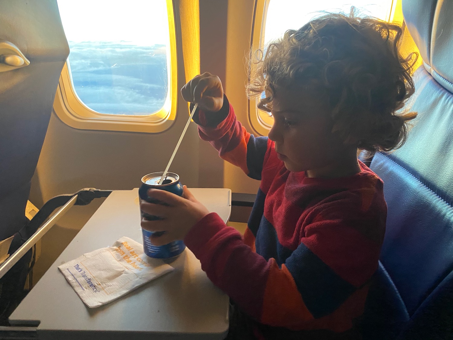 a child sitting in a chair with a can of soda