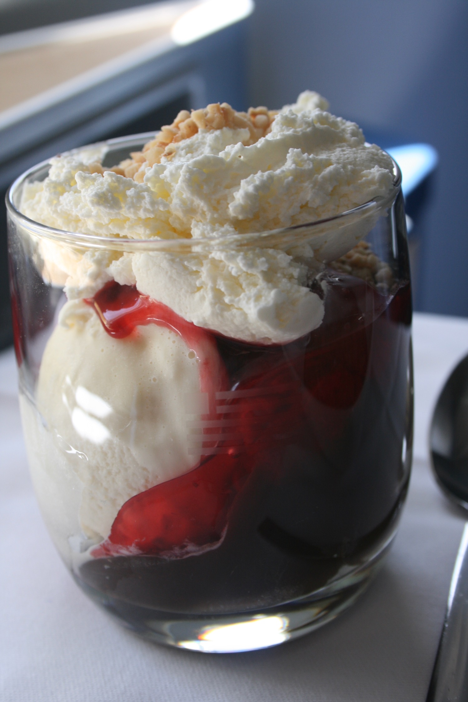 a glass of ice cream with red liquid and a spoon