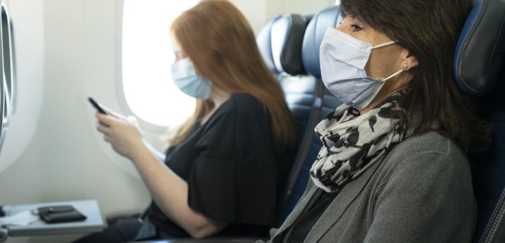 a woman wearing a mask and gloves while sitting on an airplane