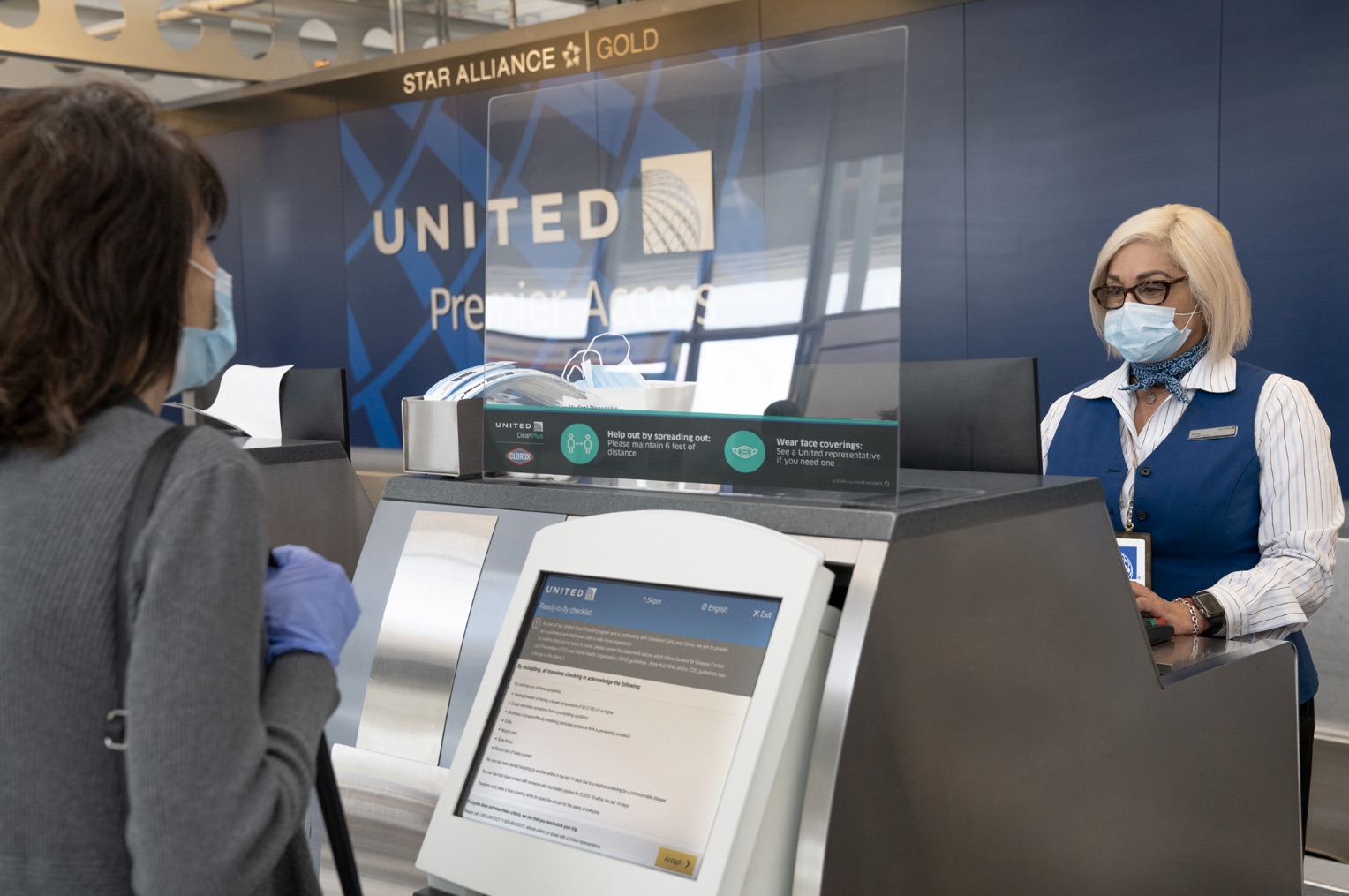 a group of people wearing face masks and standing at an airport check-in counter