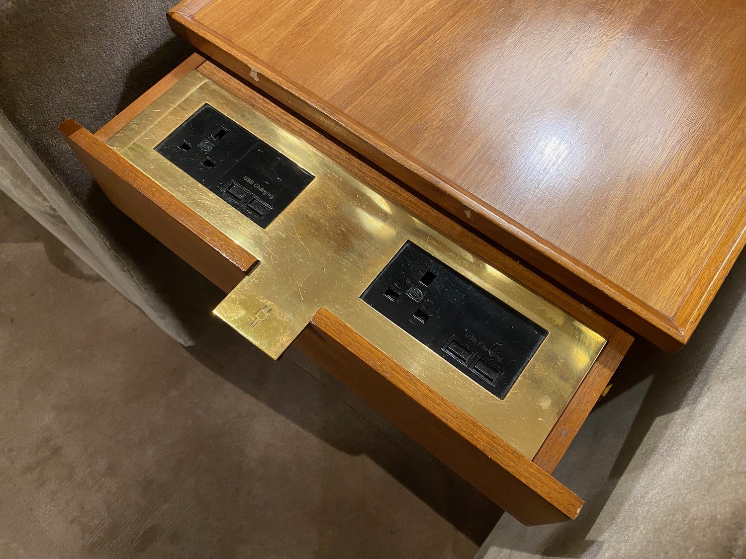 a table with a wood surface and a gold plated outlet
