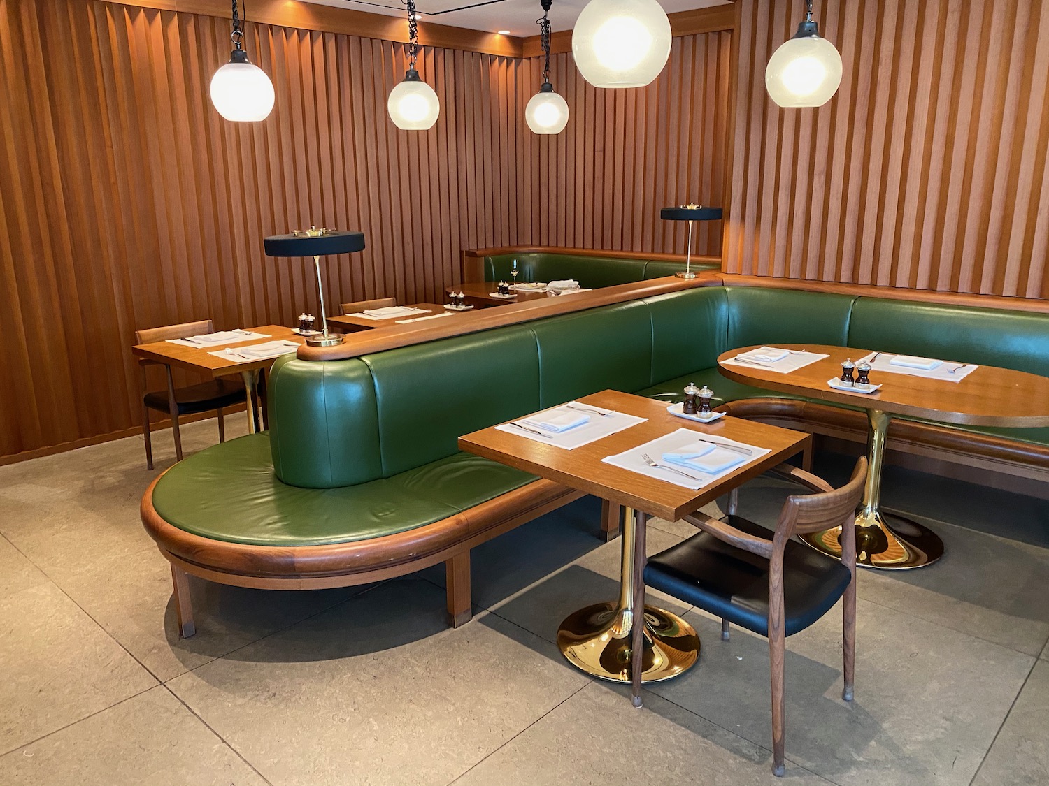 a booth seating with green leather and gold chairs