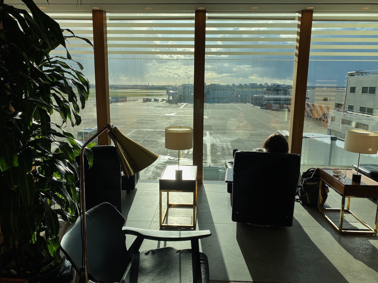 a person sitting in a chair looking out a window at an airport