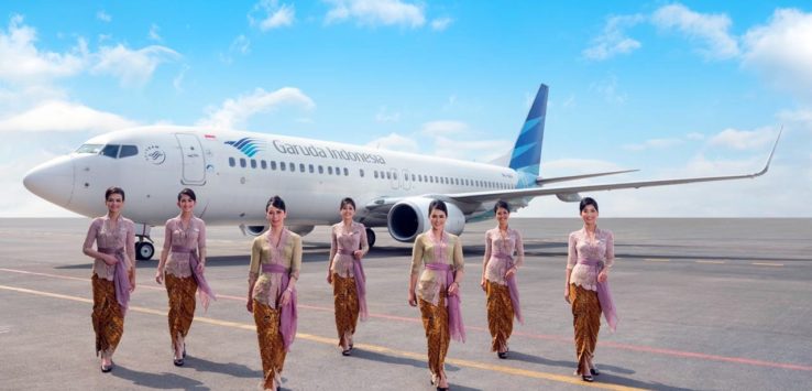 a group of women in traditional dress standing in front of an airplane