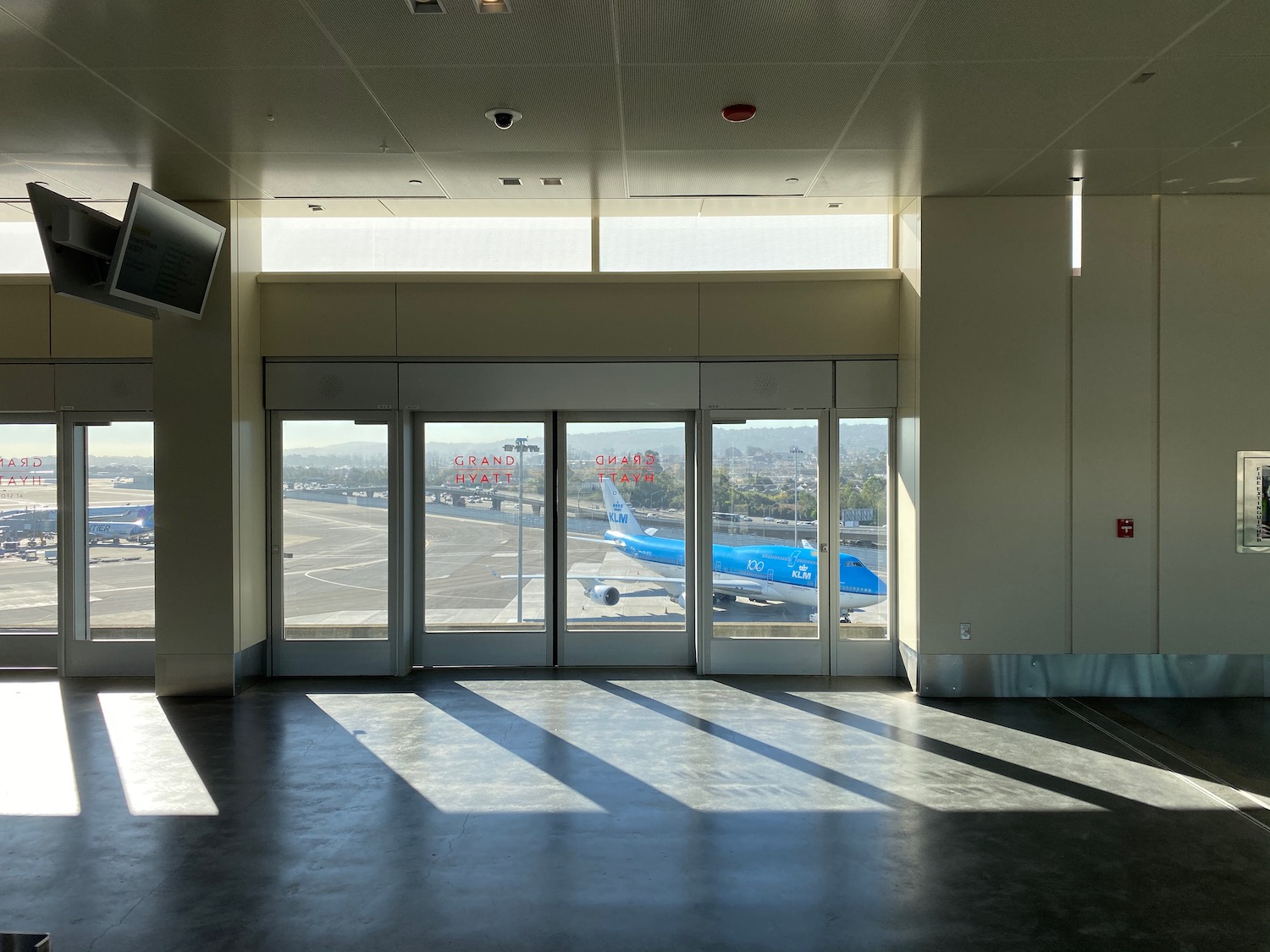 an empty room with glass doors and a plane in the background